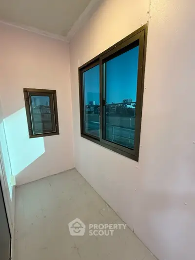 Cozy balcony with city view and large windows, perfect for relaxation.