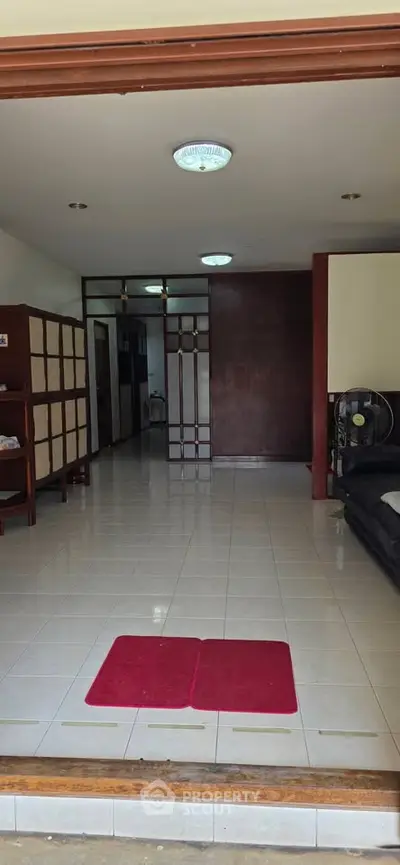 Spacious living area with tiled flooring and wooden accents, perfect for modern living.