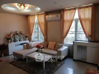 Elegant living room with cozy L-shaped sofa, chic decor, and natural light from large windows.