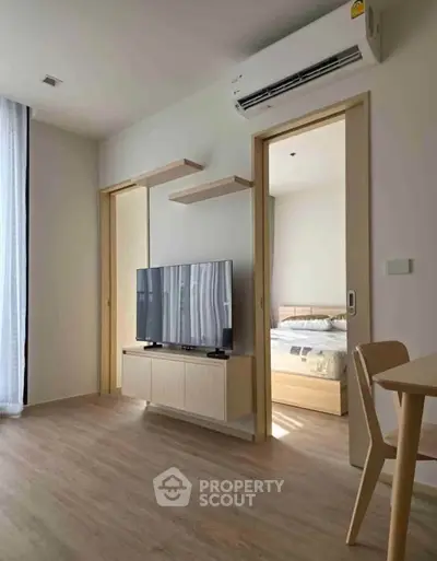 Modern living room with sleek TV setup and glimpse into cozy bedroom