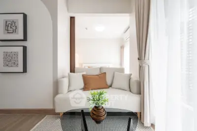 Modern living room with cozy white sofa, stylish decor, and natural light through large windows.