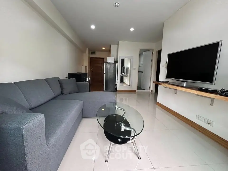 Modern living room with sleek furniture and large TV in a stylish apartment.