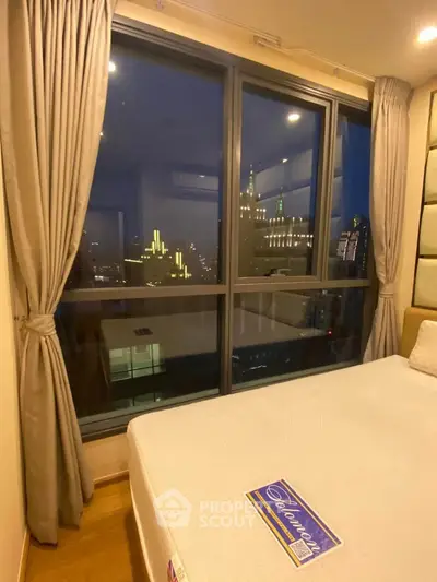 Luxurious bedroom with stunning city view through large windows, elegant curtains, and cozy bed.