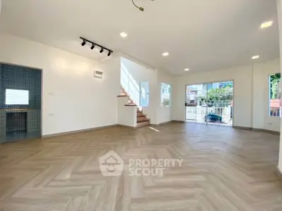 Spacious modern living room with herringbone flooring and ample natural light.