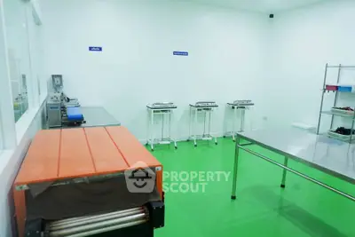 Spacious industrial kitchen with stainless steel tables and green flooring
