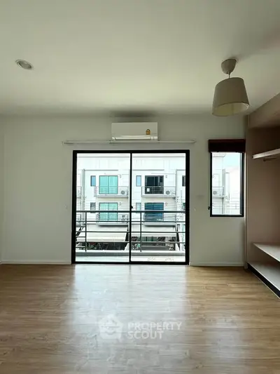Spacious living room with large window and balcony view in modern apartment.