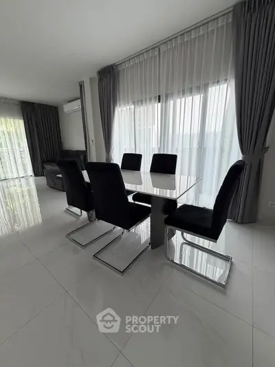 Spacious modern dining area with sleek black chairs and elegant curtains, perfect for entertaining guests.