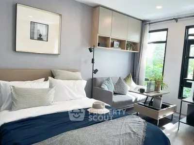 Stylish modern bedroom with cozy seating area and large windows for natural light.