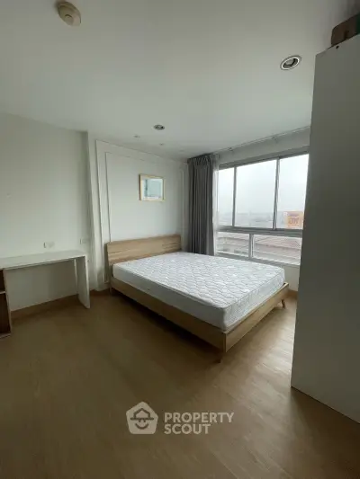 Spacious bedroom with large window and natural light in modern apartment