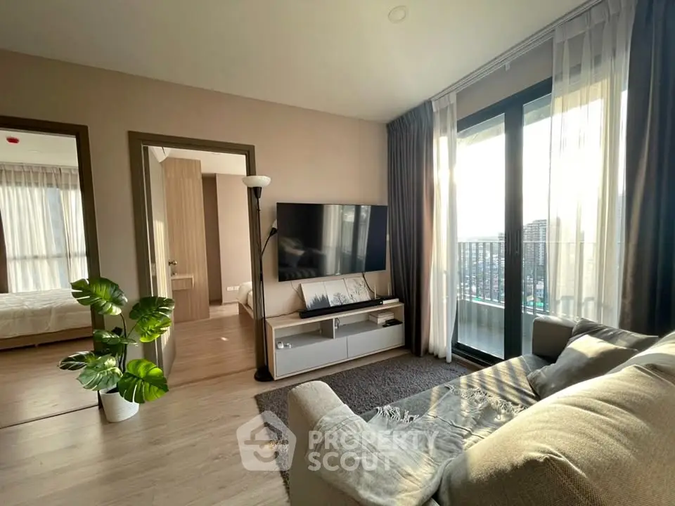 Modern living room with large TV, cozy sofa, and balcony view in a stylish apartment.
