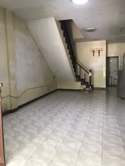 Spacious interior with staircase and tiled floor, ideal for renovation.