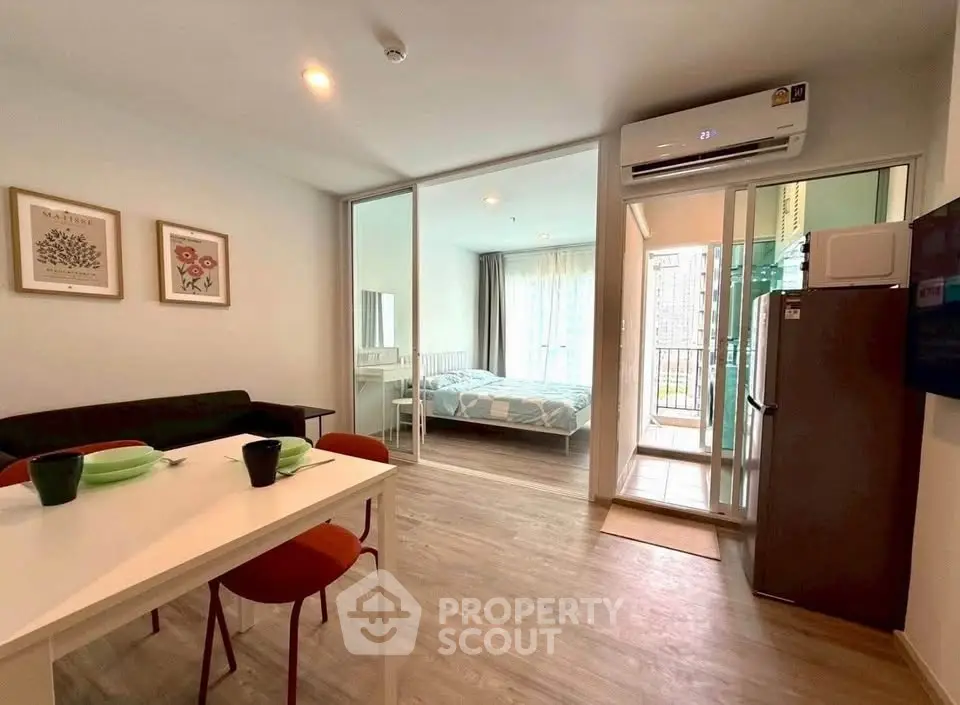 Modern open-plan living room with dining area and bedroom, featuring sleek decor and natural light.