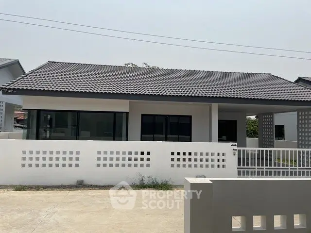 Modern single-story house with sleek design and spacious driveway in a serene neighborhood.