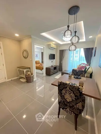 Elegant living room with modern decor and stylish lighting, featuring a cozy seating area and a glimpse of the bedroom.