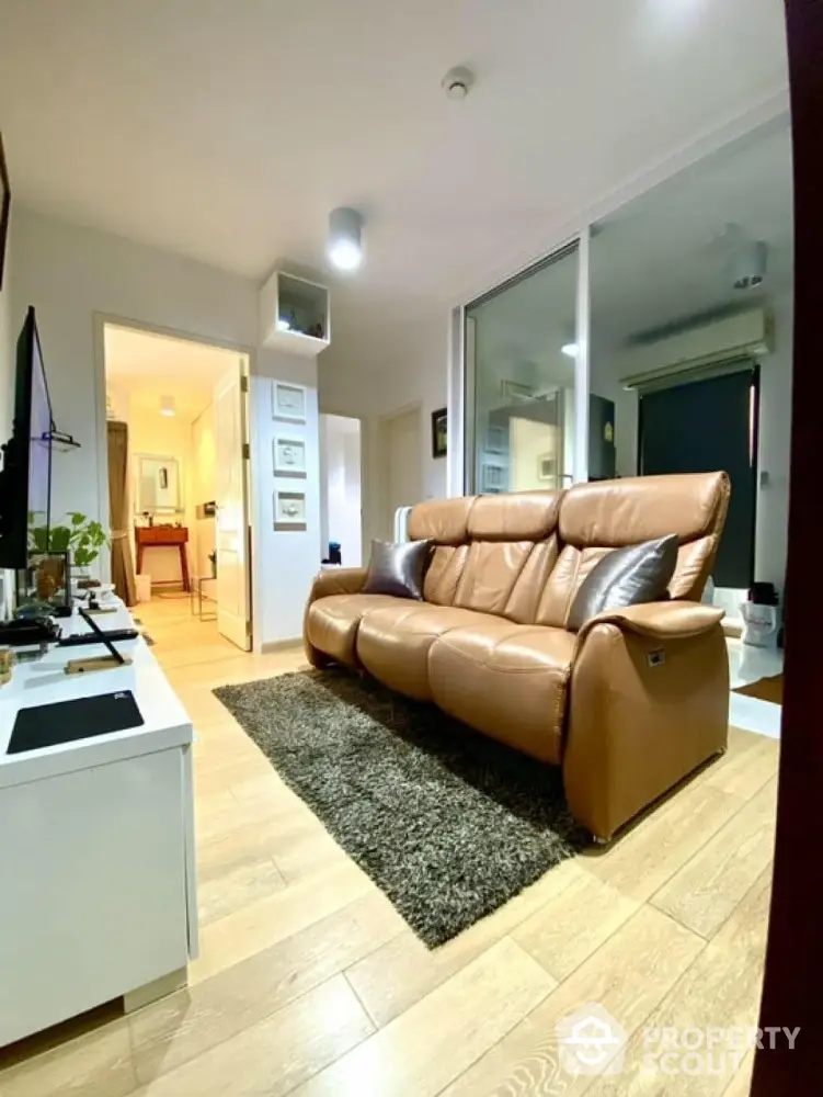 Modern living room with leather sofa and wooden flooring, open layout design.