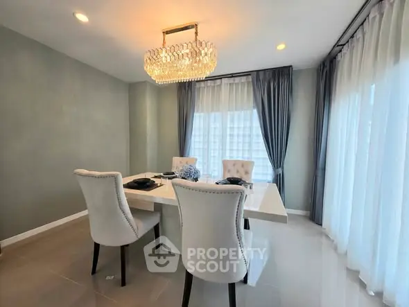 Elegant dining room with modern chandelier and stylish chairs in a bright, airy space.