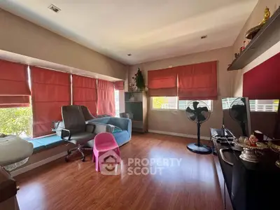 Cozy living room with wooden flooring, red blinds, and modern furniture.