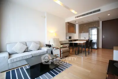 Modern living room with open kitchen, stylish furniture, and wooden flooring in a contemporary apartment.