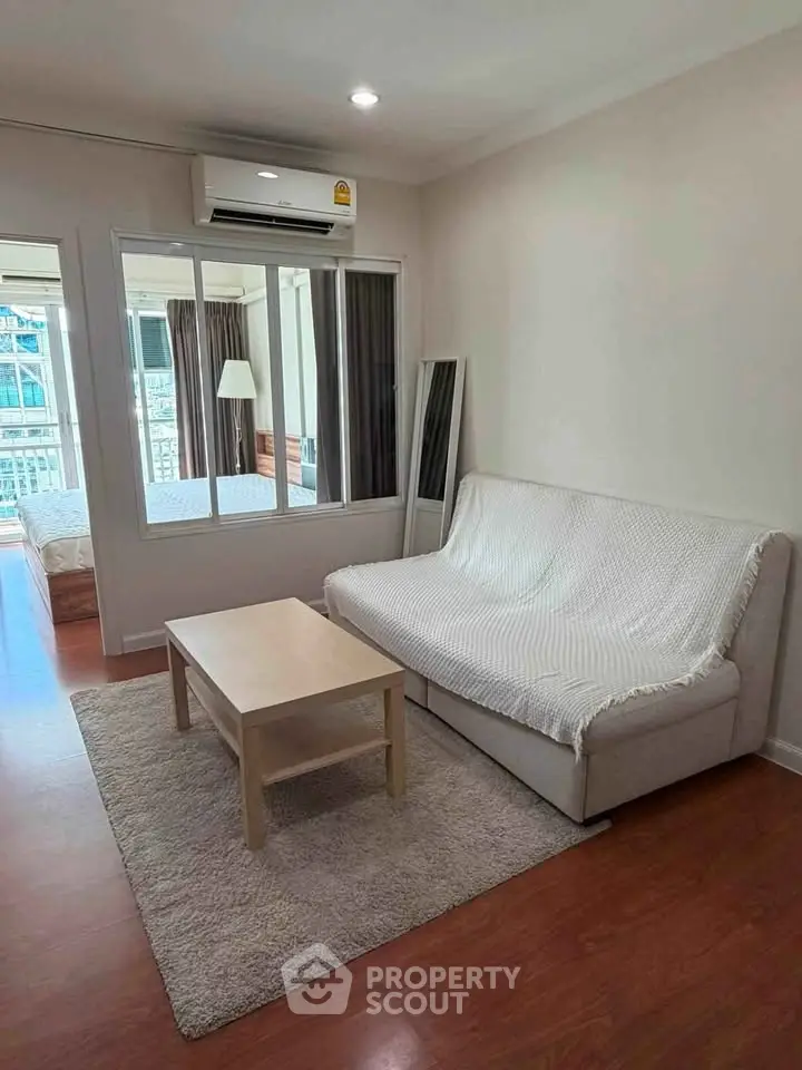 Cozy living room with modern decor and view into a bright bedroom, perfect for urban living.