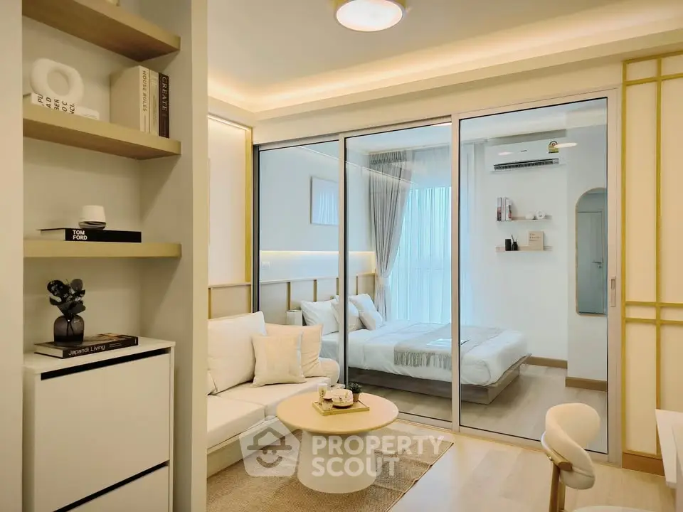 Modern open-concept living room with sliding glass doors to bedroom, featuring stylish decor.
