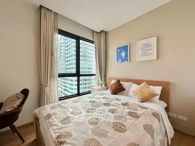 Cozy bedroom with large window offering city view, stylish decor, and comfortable bedding.