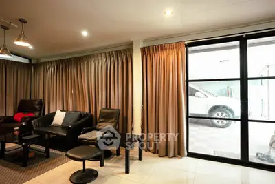Spacious living room with modern furniture and large windows overlooking a carport.
