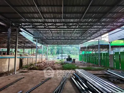 Spacious industrial warehouse under construction with metal framework and open layout.