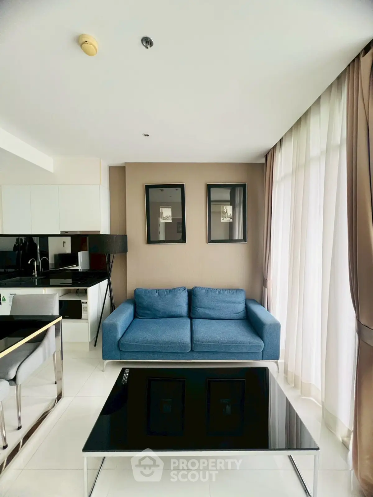 Modern living room with blue sofa and sleek kitchen in open layout apartment.