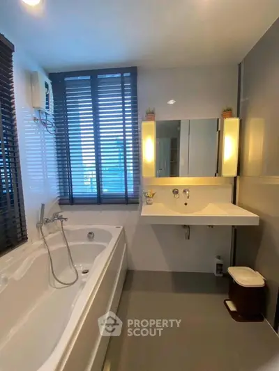 Modern bathroom with sleek design and large bathtub, featuring elegant lighting and stylish blinds.