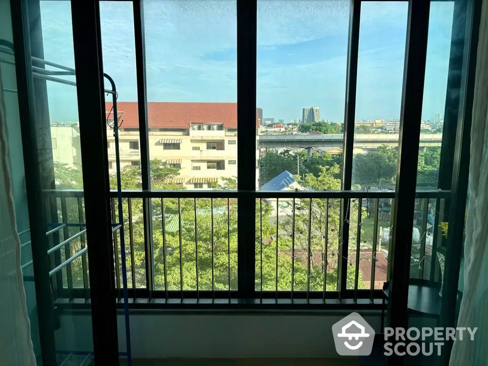 Stunning city view from a modern apartment balcony with large glass windows.