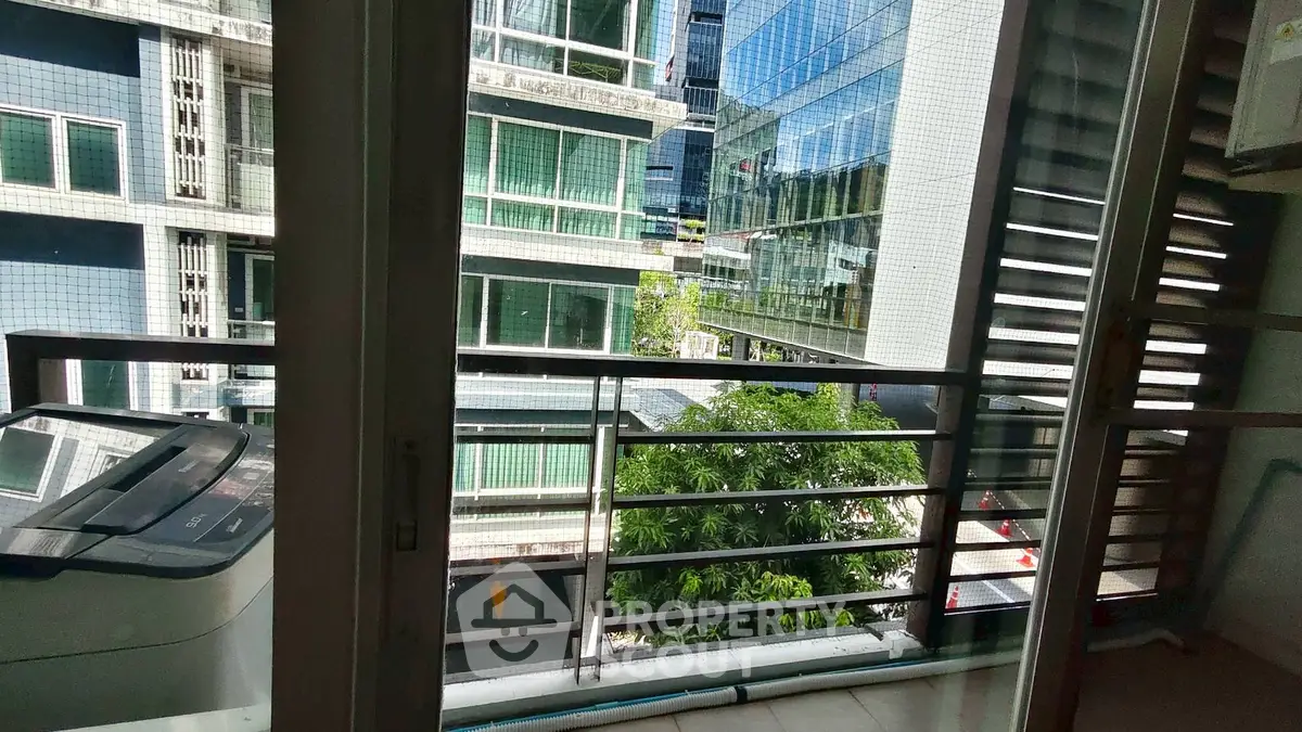Modern apartment balcony with city view and nearby buildings.