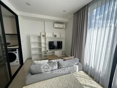 Modern living room with cozy sofa, TV, and large window in a stylish apartment.
