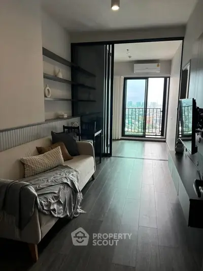 Modern living room with balcony and city view, featuring sleek furniture and open layout.