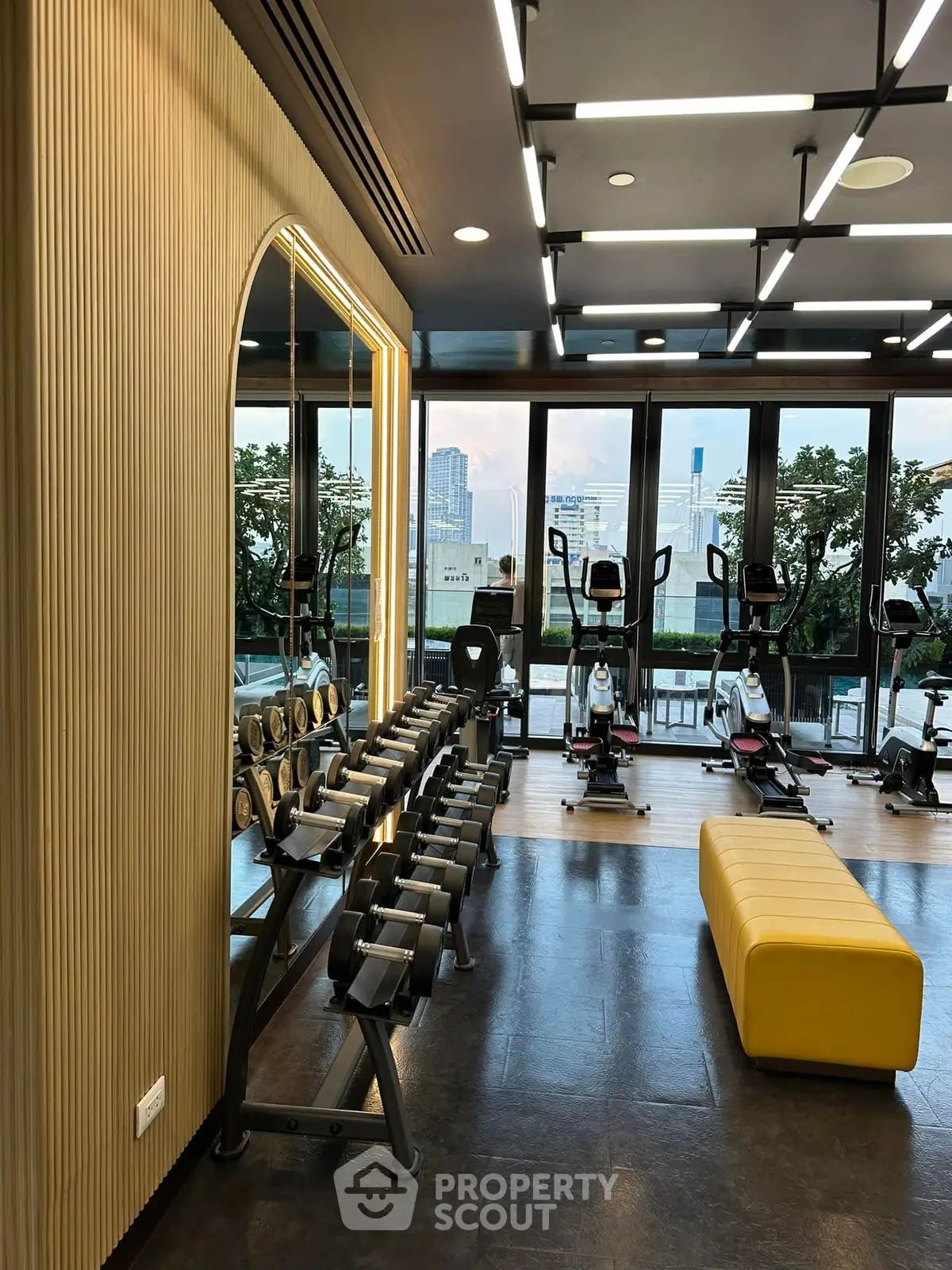 Modern gym with city view, featuring exercise equipment and stylish lighting.