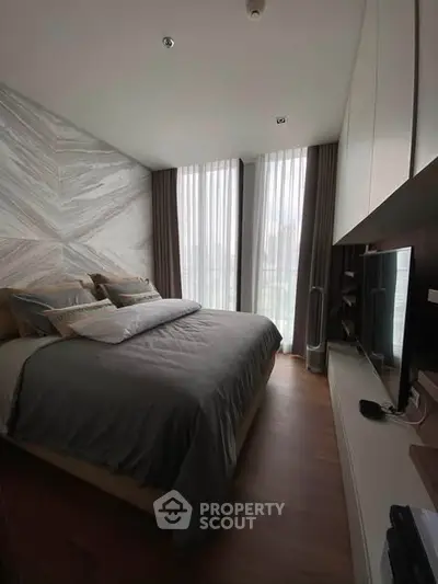 Luxurious bedroom with modern decor and large windows offering natural light.