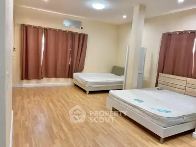 Spacious bedroom with wooden flooring and two beds, ideal for comfort and relaxation.