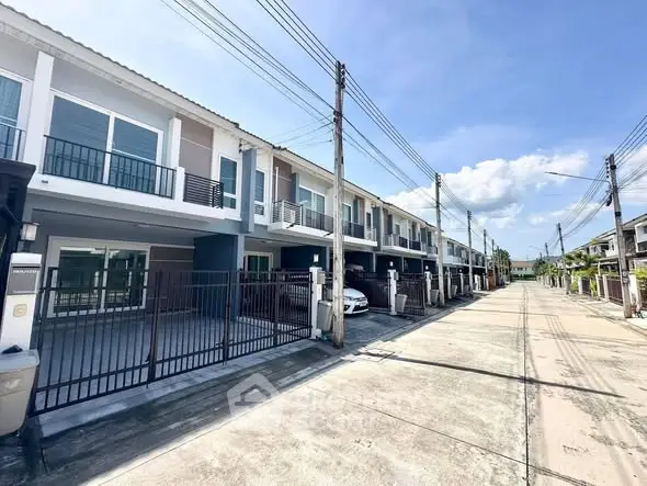 Modern townhouse row with balconies and garages in a sunny residential area.