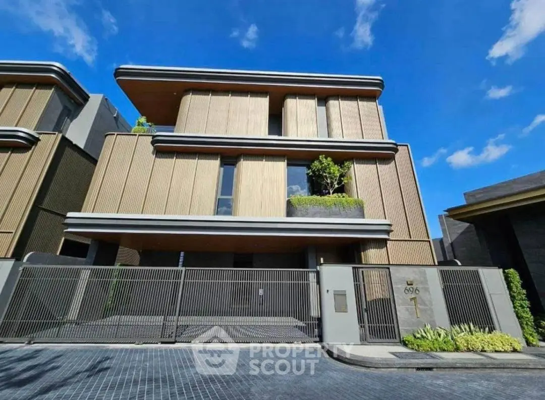 Modern luxury house exterior with sleek design and spacious driveway under clear blue sky.