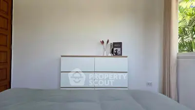 Minimalist bedroom with white dresser and natural light from window