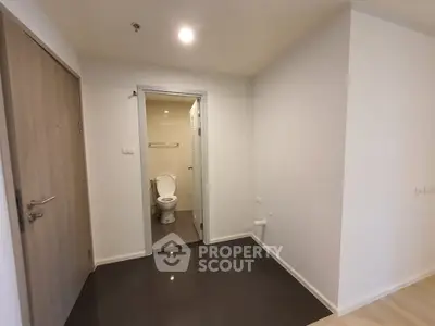 Compact apartment entrance with visible bathroom, modern design, and neutral tones.