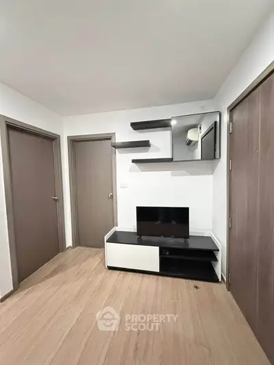Modern living room with sleek TV stand and wall shelves, featuring minimalist design and wooden flooring.