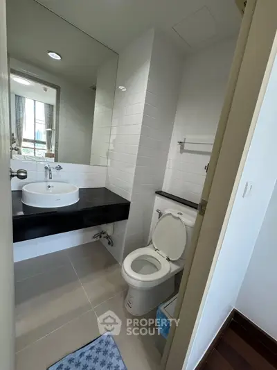 Modern bathroom with sleek fixtures and large mirror in a contemporary apartment.