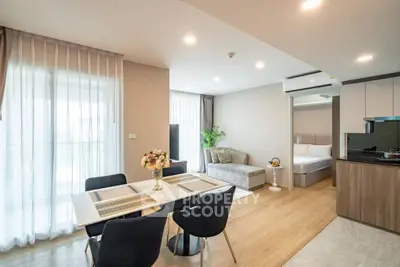 Modern open-plan living room with dining area and bedroom, featuring elegant decor and natural light.