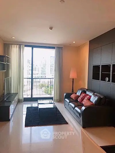 Modern living room with city view, sleek black sofa, and large windows.