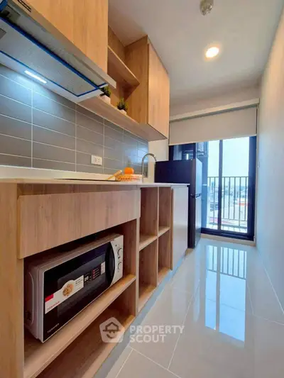 Modern kitchen with sleek cabinetry and balcony view in a stylish apartment.