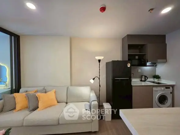 Modern living room with cozy sofa, compact kitchen, and washing machine.