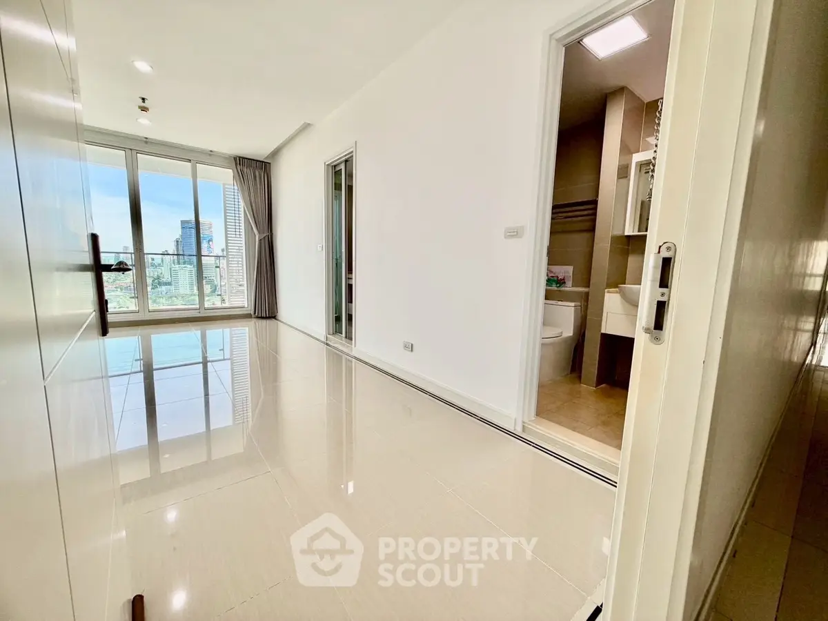 Spacious modern apartment with city view and sleek tiled flooring, featuring a bright open layout.