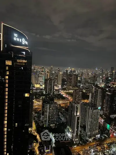 Stunning nighttime cityscape view from a high-rise building, showcasing vibrant urban lights and skyline.