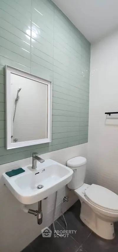 Modern bathroom with sleek fixtures and stylish green tile accent wall.