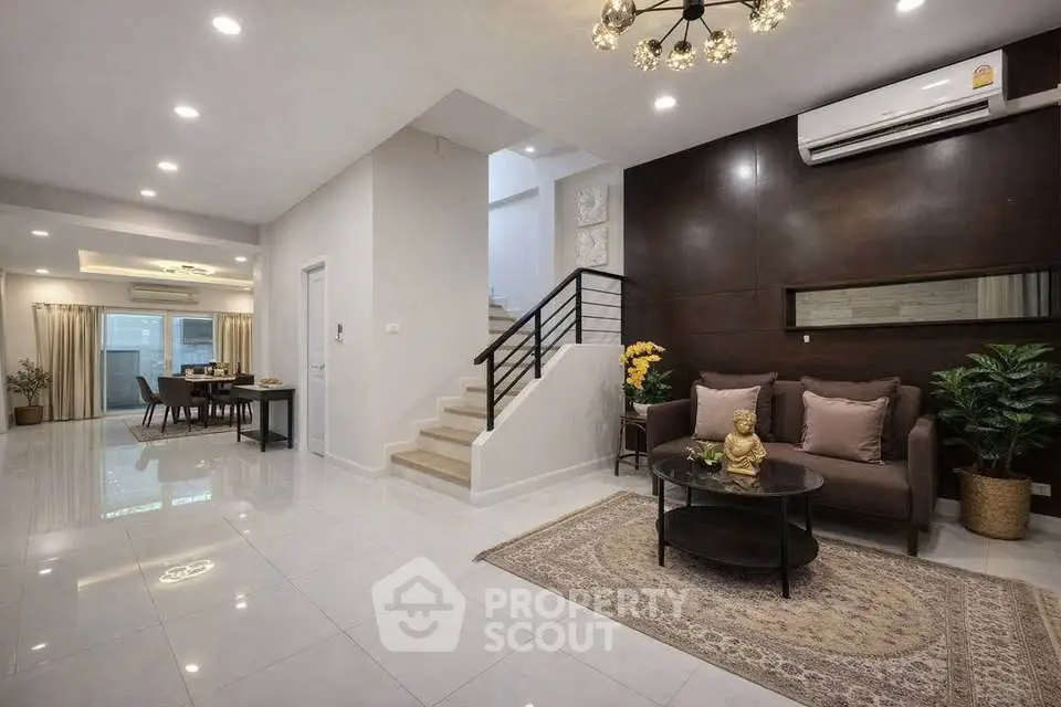 Spacious modern living room with elegant decor and open dining area, featuring stylish lighting and cozy seating.